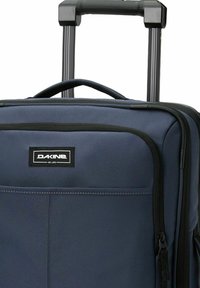 Valigia rigida blu navy con manico telescopico e tasca anteriore con zip, logo del marchio Dakine visibile.