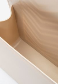 Contenitore di stoccaggio in plastica beige con superficie interna liscia e bordi arrotondati, caratterizzato da sottili riflessi di luce e senza motivi visibili.