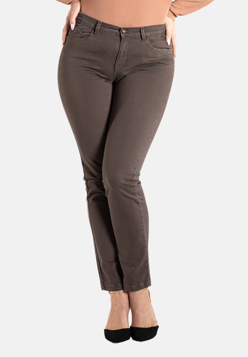 Jeans stretch marron avec une coupe slim, dotés de cinq poches et de détails de couture subtils, associés à des chaussures à talons hauts noires.
