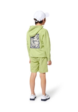 Hoodie vert avec graphique au dos, shorts assortis et baskets blanches avec le logo "BOSS". Comprend une casquette blanche. Texture lisse.