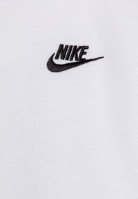 Witte katoenen T-shirt met een geborduurd zwart Nike-logo op de linker borst. Zachte textuur en minimalistisch ontwerp.
