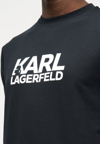 Μαύρο t-shirt με στρογγυλή λαιμόκοψη και έντονο λευκό λογότυπο "KARL LAGERFELD" τυπωμένο στο στήθος.