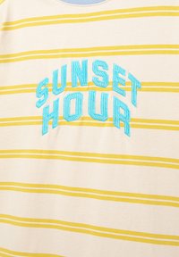 Striped short-sleeve shirt in cream with yellow and white stripes. Features blue embroidered text "SUNSET HOUR" at the center.