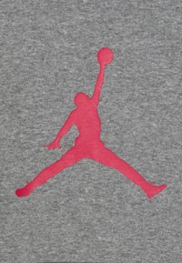 Tessuto di cotone grigio con una grande silhouette rosa di una persona che compie un salto, con un pallone da basket sopra la testa.