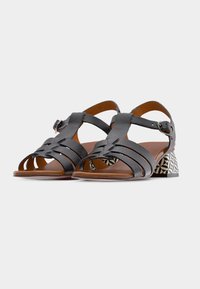 Μαύρα δερμάτινα σανδάλια με ανοιχτό δάχτυλο, πολλαπλούς ιμάντες, ρυθμιζόμενο αγκράφα και γεωμετρικό τακούνι σε σχέδιο μπλοκ. Λείο υλικό και κλασικός σχεδιασμός.