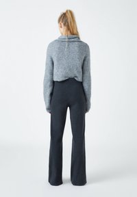 Pull en maille gris avec col bénitier, associé à un pantalon à jambes larges taille haute gris foncé. Texture douce et coupe décontractée.