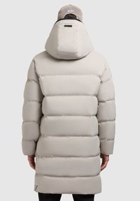 Lys grå pufferjakke med hætte, elastiske manchetter og en lang, slank form med syede sektioner til isolering.