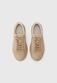 Sneakers in suede beige con punta arrotondata, superficie testurizzata, lacci piatti e suola in gomma. Design leggero con caratteristiche minimaliste.