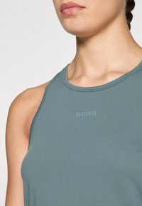 Lichtblauw mouwloos sporttop met ribbeltextuur en een ronde halslijn, met op de voorkant de reliëftekst "BORG".