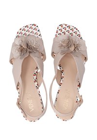 Beige sandalen met bloemaccenten op de banden, vierkante neus en een geprofileerde binnenzool met patronen van driehoeken in rood en zwart.