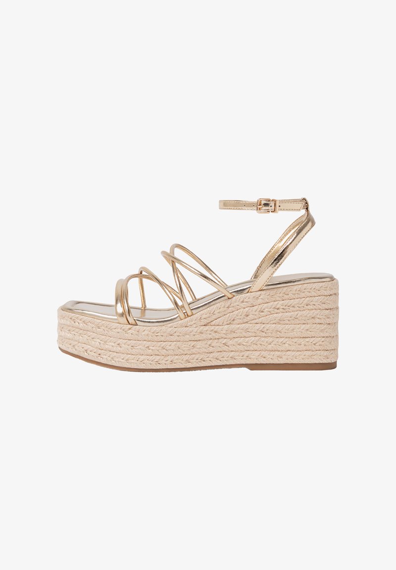Sandales compensées métalliques dorées avec une plateforme en jute tressé, dotées de plusieurs fines lanières et d'une boucle à la cheville pour un bon maintien.