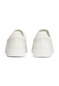 Weiße Ledersneaker mit glatter Oberfläche, gepolstertem Fersenbereich, subtilen Nähdetails und einer Gummisohle mit Grip-Muster.