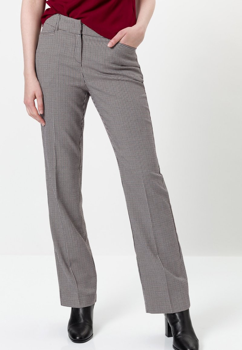 Pantalons à motif pied-de-poule noir et blanc, jambe droite, taille mi-haute et poches, associés à des bottines noires.