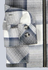 Karierte Jacke mit blau-weißem Karo-Muster, mit umgeschlagenem Ärmelbündchen, silbernen Knöpfen und einem schwarzen Reißverschluss vorne.