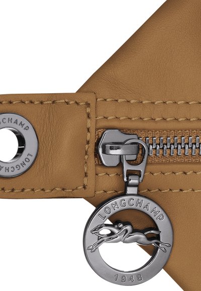 Tan leather with visible stitching, featuring a silver zipper and a round metal charm displaying a running horse, marked "LONGCHAMP 1948."