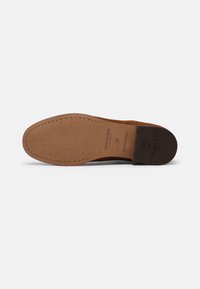 Semelle de chaussure en suède marron avec un design texturé, présentant une couture, un logo embossé et un talon noir contrastant. Taille 42.