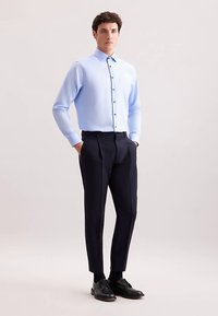 Lichtblauw overhemd met lange mouwen, gecombineerd met op maat gemaakte donkerblauwe broek en zwarte schoenen, met een gladde textuur.