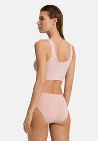 Ljusrosa bralette med breda axelband och matchande hög midja-trosor. Mjuk, slät tyg med en sömlös design och ingen synlig utrustning.