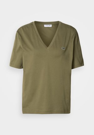 T-shirt en coton vert olive avec un décolleté en V et des manches courtes. Présente un petit logo de crocodile brodé sur la poitrine gauche.