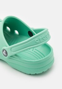 Sandały Cros w kolorze turkusowym, wykonane z miękkiej gumy, z teksturowaną wkładką, paskiem na górze oraz otworami do drenażu dla lepszej wentylacji.