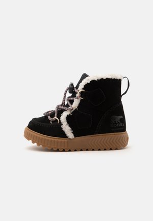 Botte d’hiver noire imperméable avec semelle en caoutchouc marron, doublure en polaire blanche, lacets roses et noirs, et logo Sorel sur le côté.