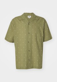 Camicia a maniche corte in tessuto verde oliva con motivi geometrici bianchi, davanti con bottoni e colletto classico. Texture morbida e vestibilità comoda.