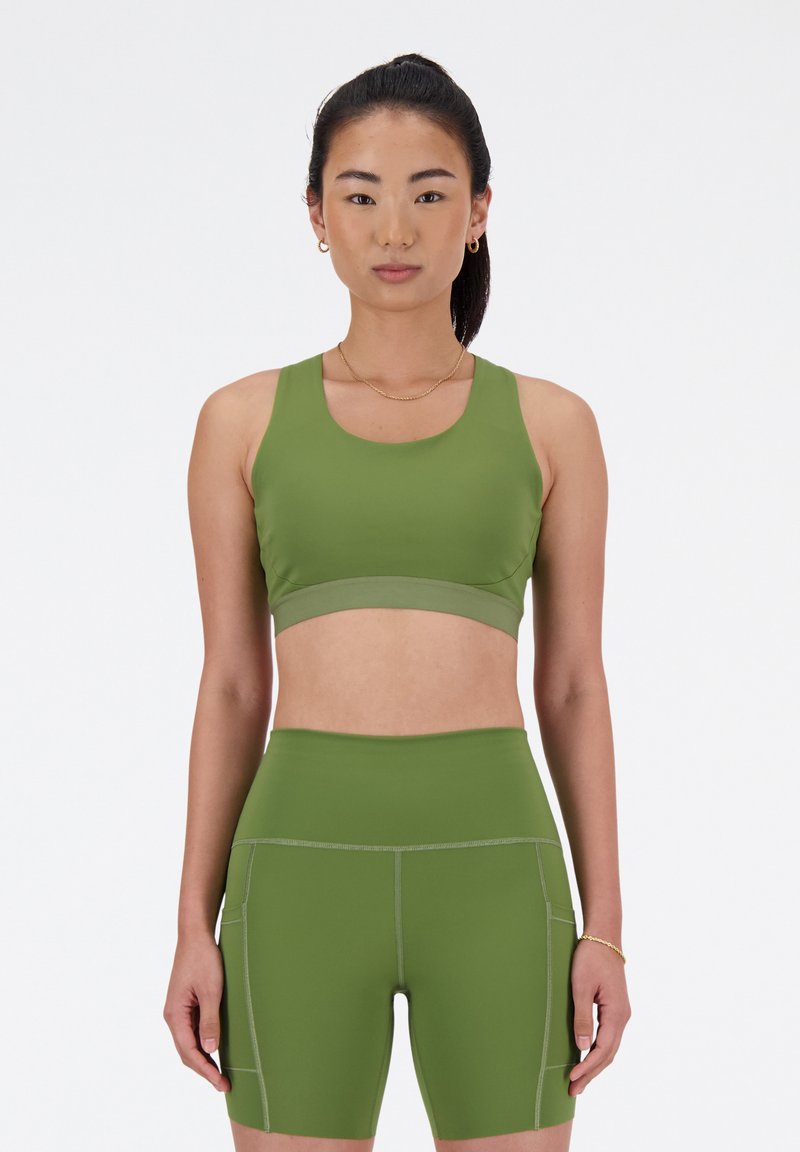 Grüner Sport-BH und passende hochtaillierte Shorts, hergestellt aus dehnbarem Stoff. Mit Flachnähten und glatter Textur.
