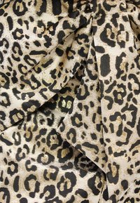 Leoparda raksta audums bēšā un melnā krāsā ar teksturētu virsmu un metālisku zelta akcentu. Raksts ietver dažādas formas un izmērus.