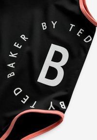 Fekete fürdőruha, közepén egy nagy fehér "B"-vel, körülötte a "TED BAKER BY" felirattal. Rózsaszín részletekkel díszített, sima textúrájú.