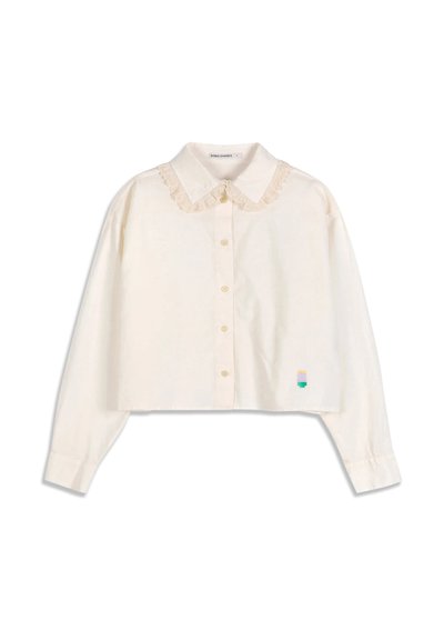 Blouse courte à manches longues couleur crème avec col Peter Pan bordé de dentelle, boutonnière devant et petit détail brodé multicolore près de l'ourlet.