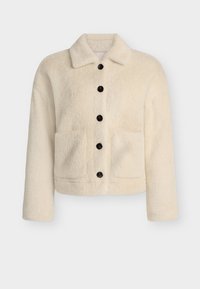 Kremo spalvos flisinė striukė su apykakle, priekyje esančiu mygtukų uždarymu ir dviem kišenėmis. Savybės: juodi mygtukai ir tekstūruota, minkšta medžiaga.