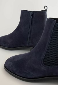Botas de tobillo de ante azul marino con un acabado suave, que cuentan con una cremallera lateral y un panel de malla texturizada, punta redondeada y suela plana de goma.
