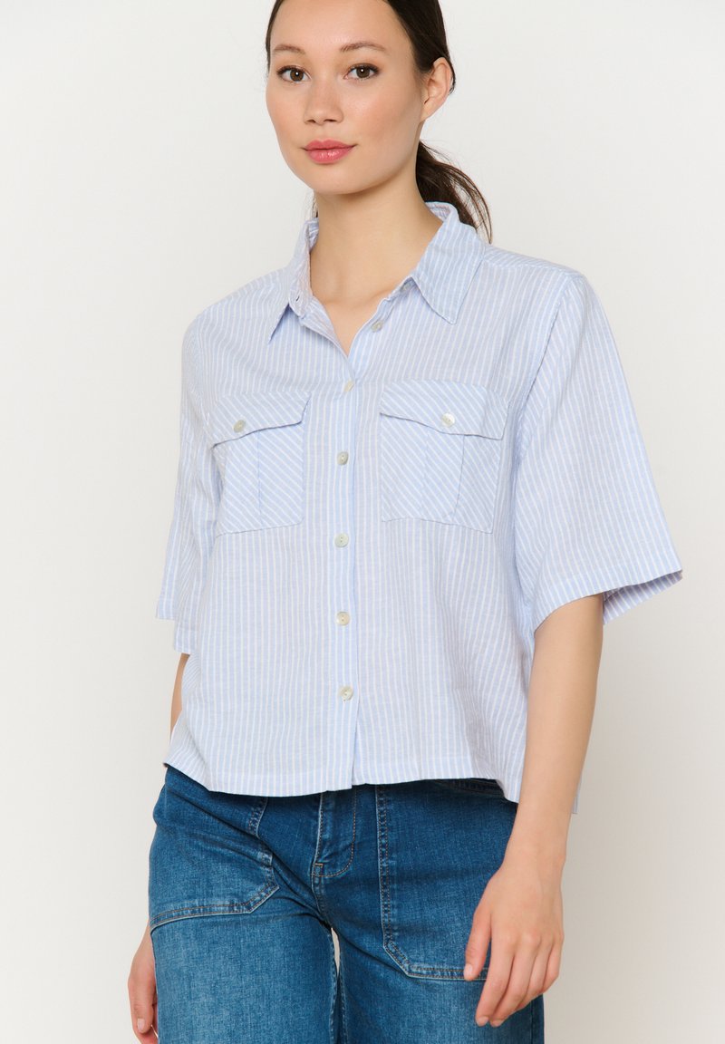 Camicia a maniche corte a strisce blu e bianche con due tasche sul petto, chiusura con bottoni e tessuto morbido e leggero. Vestibilità casual e rilassata.