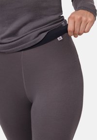 Leggings grigi aderenti con una texture liscia e una vita elastica nera. Un piccolo tag con il logo è visibile sulla vita.