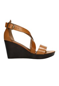 Sandale compensée en cuir beige avec un design de sangle croisée, sangle de cheville réglable et semelle compensée contrastante foncée. Texture lisse tout au long.