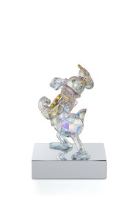 Kristallfigur von Donald Duck, mit facettierten Oberflächen, die das Licht in mehreren Farben reflektieren, steht auf einer spiegelnden Grundplatte.