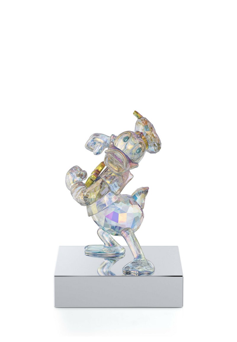 Kristallfigur von Donald Duck, mit facettierten Oberflächen, die das Licht in mehreren Farben reflektieren, steht auf einer spiegelnden Grundplatte.