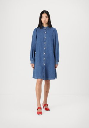Denim shirt dress with long puff sleeves, button front, and a slight A-line shape. Bright red high-heeled shoes with a pointed toe.