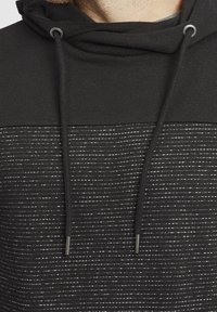 Sudadera negra con capucha y un patrón de rayas texturizadas. Incluye cordones metálicos y un diseño de paneles en contraste. Material de mezcla de algodón suave.