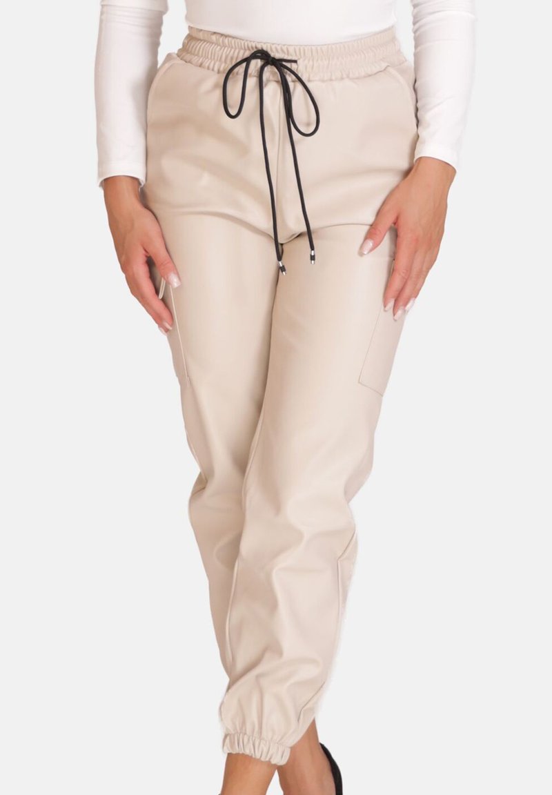 Beżowe spodnie typu jogger z imitacji skóry z elastycznym pasem, regulowanym sznurkiem i elastycznymi ściągaczami, wyposażone w boczne kieszenie.