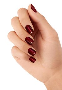 Main avec des ongles courts vernis dans une teinte bordeaux brillante, comportant un accent doré subtil le long de la cuticule. Le teint est clair.