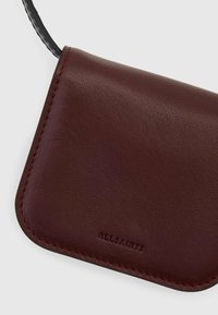 Portafoglio in pelle bordeaux con texture fine, bordi cuciti e logo del marchio impresso. Forma rettangolare compatta con un design minimal.
