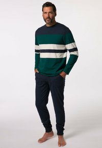 Chemise à rayures vertes et bleu marine à manches longues avec un col rond, associée à un pantalon bleu marine avec poches et revers aux chevilles.