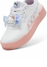 Zapatilla blanca con suela de goma rosa, adornada con un lazo azul y un gráfico de Hello Kitty. Presenta un panel lateral con un patrón. Textura suave.