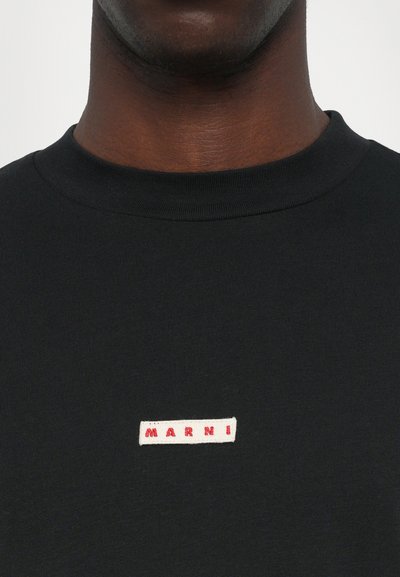Musta puuvillane T-särk, millel on ribitud ringkaelus ja väike ristkülikukujuline logopatch, millel on punane tekst "MARNI" valge tausta peal.