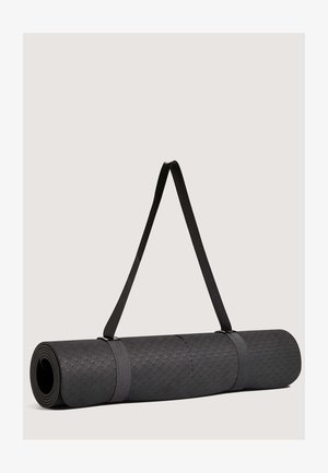 Čierna jogová podložka zvinutá, vyrobená z textúrovaného materiálu, zabezpečená šedými popruhmi na prenášanie. Na povrchu má geometrický vzor.