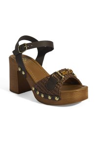 Braune geflochtene Plattform-Sandale mit einem dicken Holzabsatz, ausgestattet mit einem dunklen Riemen und goldenen Hardware-Details. Runde Zehenform und gepolsterte Innensohle.