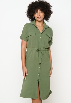 Robe chemise vert olive en tissu doux, dotée de manches courtes, de deux poches poitrine, d'une fermeture à boutons et d'une taille ceinturée pour mettre en forme.