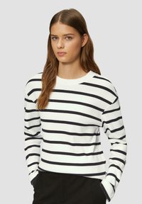 Maglione bianco con strisce orizzontali nere, texture a coste, scollo rotondo e maniche lunghe. Dettaglio notevole: bottoni decorativi sui polsini.
