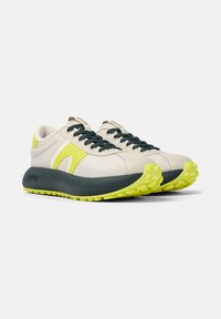 Sneaker beige e grigi con tomaia texturizzata, accenti gialli a contrasto e suola spessa con un design di battistrada a motivo.